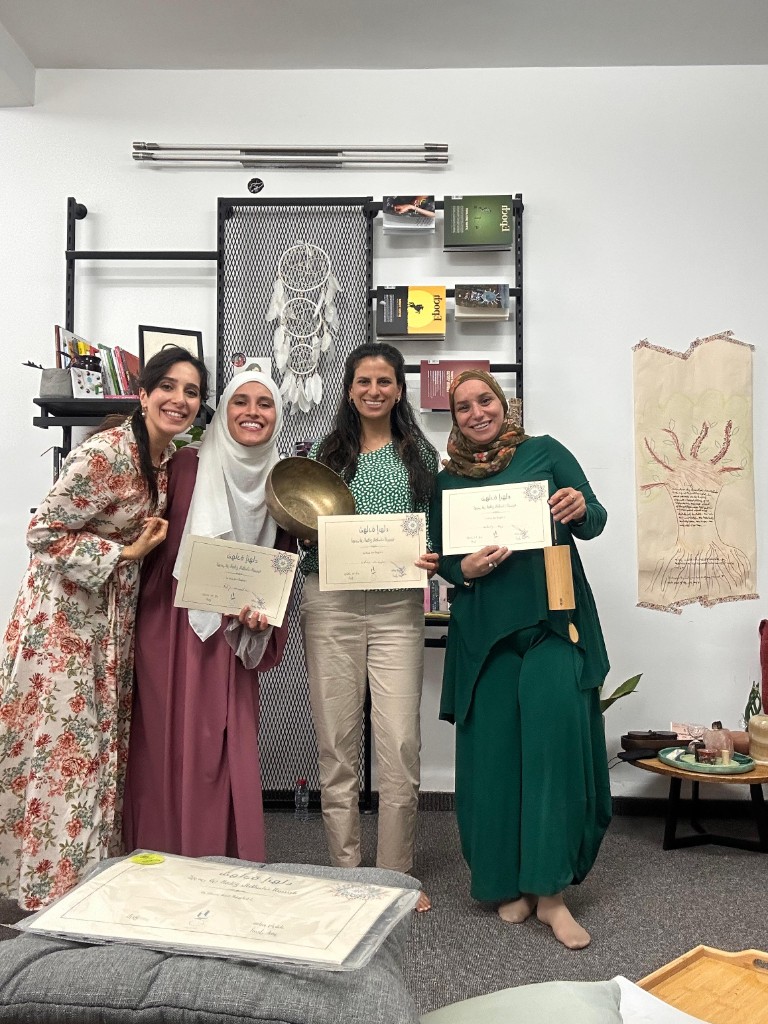 أربع مشاركات يحملن الشهادات وأدوات صوتية في قاعة تدريب مضيئة